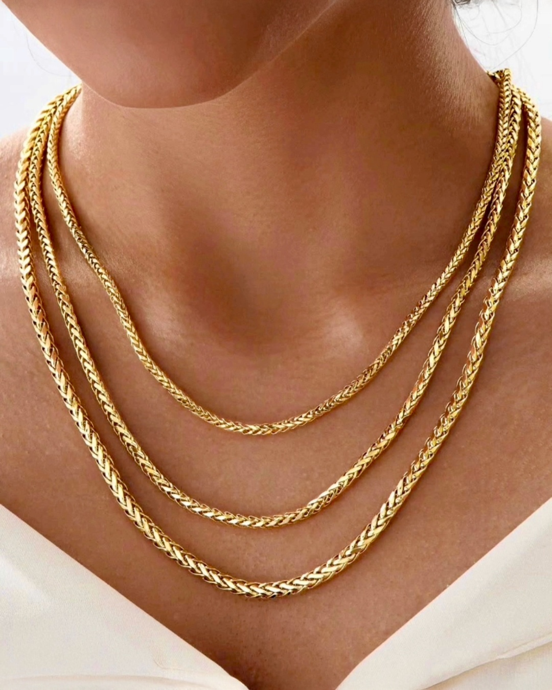 Mehrreihige 18k-Gelbgold-Halskette in geflochtener Kettenstruktur, elegant am Hals getragen, mit warmem Goldglanz auf der Haut.