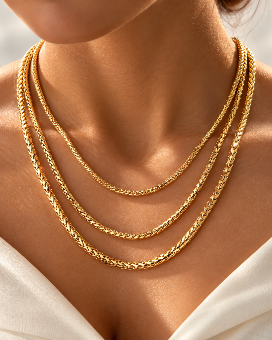 Mehrreihige 18k-Gelbgold-Halskette in geflochtener Kettenstruktur, elegant am Hals getragen, mit warmem Goldglanz auf der Haut.