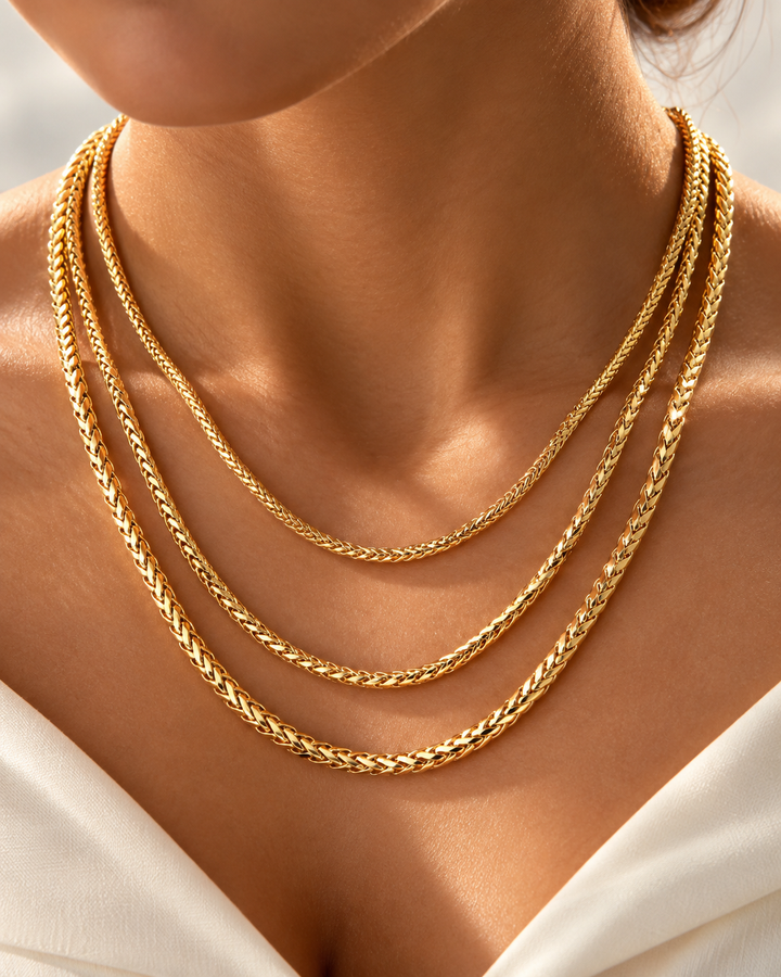 Mehrreihige 18k-Gelbgold-Halskette in geflochtener Kettenstruktur, elegant am Hals getragen, mit warmem Goldglanz auf der Haut.