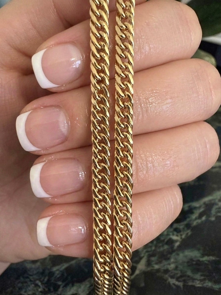 18 Karat Gelbgold Panzerkette mit diamantierter Oberfläche in Nahaufnahme. Hochwertige, massiv gefertigte Goldkette mit flachen, eng anliegenden Kettengliedern und elegantem Glanz, präsentiert auf einer Hand mit gepflegter French Manicure – zeitloser Luxus für Damen und Herren.