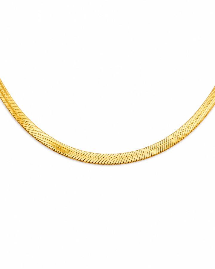 Detailaufnahme einer flachen Halskette aus 18 Karat Gelbgold mit fein strukturierter Oberfläche auf reinweißem Hintergrund.
