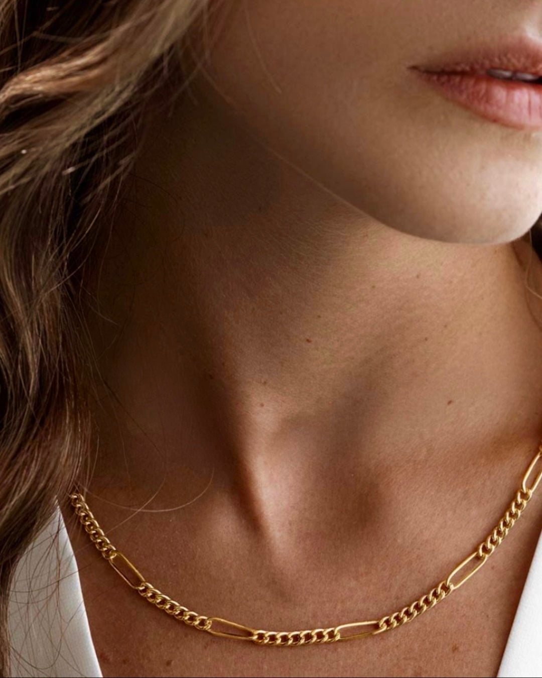 Detailaufnahme einer eleganten Halskette aus 18 Karat Gelbgold mit feiner Gliederstruktur, getragen am Hals eines Models; die polierte Oberfläche reflektiert das Licht dezent und unterstreicht die zeitlose Eleganz des Schmuckstücks.