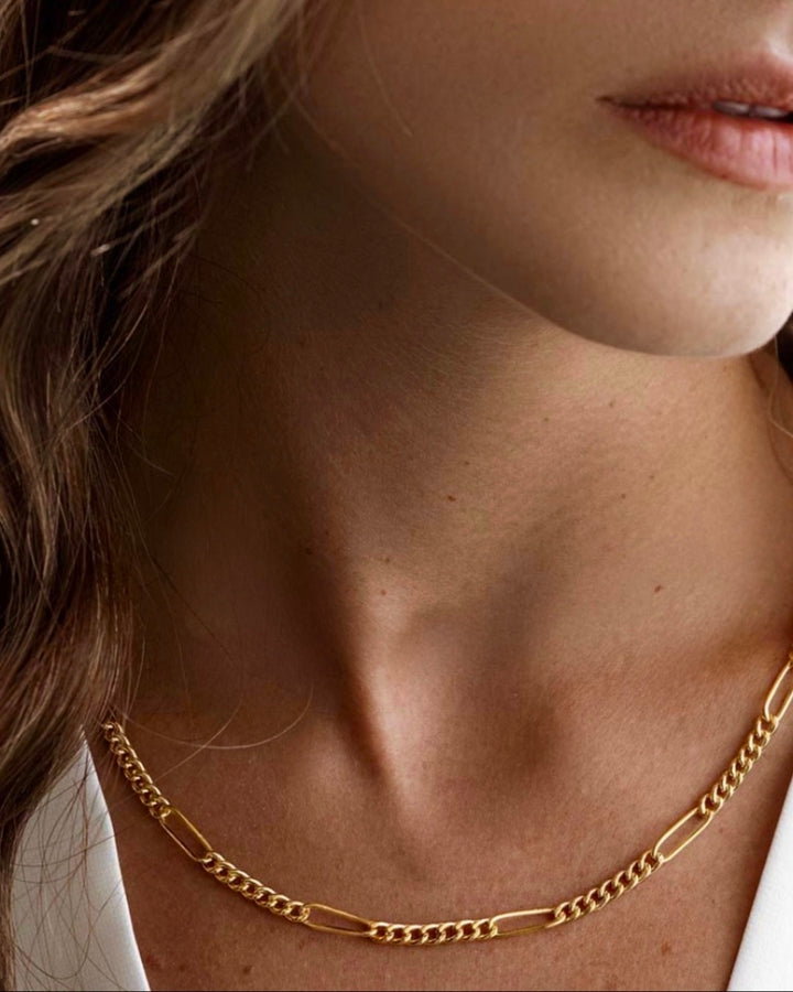 Detailaufnahme einer eleganten Halskette aus 18 Karat Gelbgold mit feiner Gliederstruktur, getragen am Hals eines Models; die polierte Oberfläche reflektiert das Licht dezent und unterstreicht die zeitlose Eleganz des Schmuckstücks.