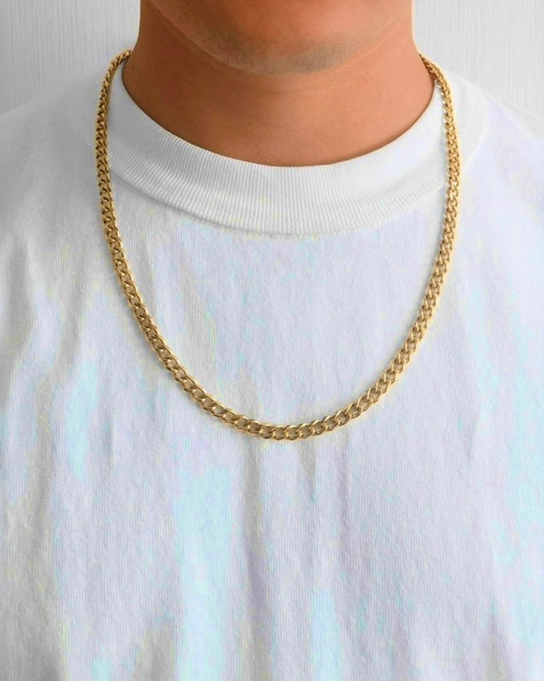 Herren-Halskette aus 18 Karat Gelbgold mit klassischer Panzerkette, getragen am Hals über weißem T-Shirt, zeitloses elegantes Design.