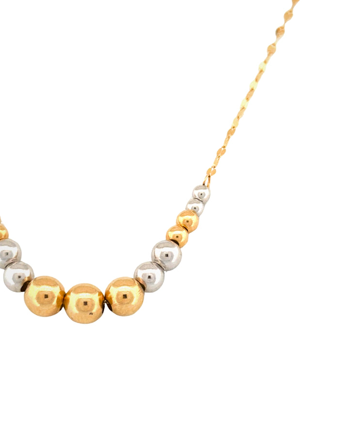 Detailaufnahme einer Halskette mit warmen Gelbgold- und kühlen Weissgoldkugeln