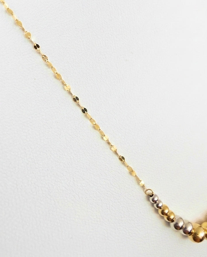 Detailaufnahme einer Halskette mit warmen Gelbgold- und kühlen Weissgoldkugeln