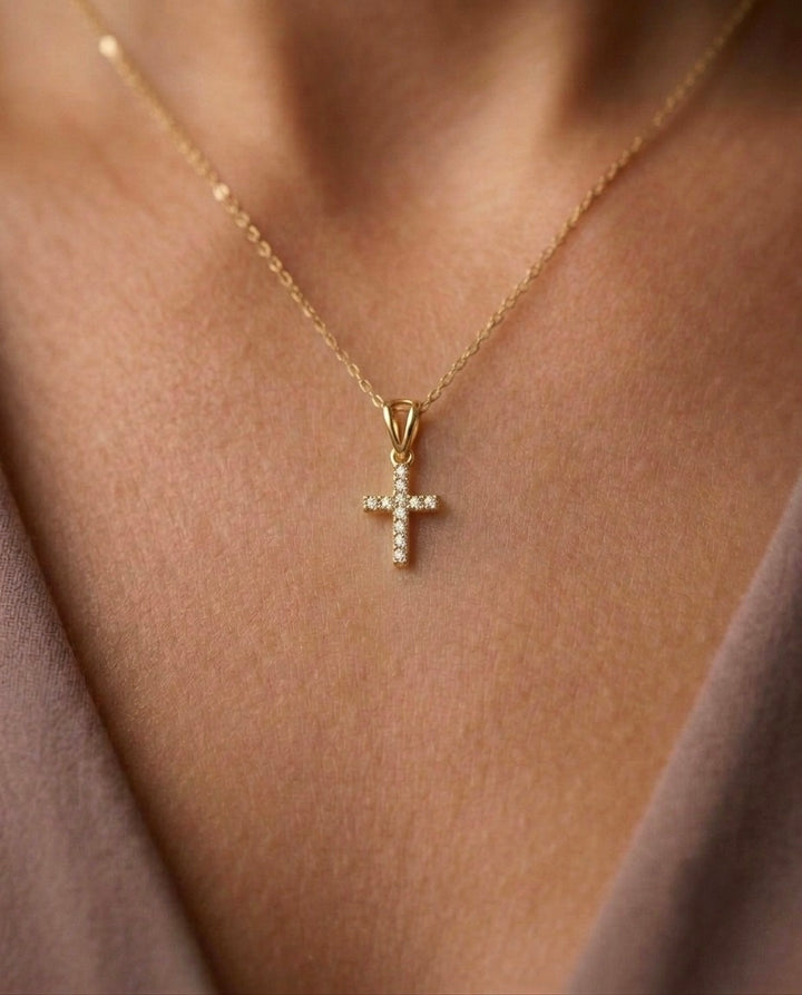 Eleganter Kreuz-Anhänger aus 18 Karat Gelbgold mit funkelnden weissen Zirkonia an einer feinen Goldkette, getragen am Dekolleté. Zeitloser Goldschmuck mit christlichem Kreuzsymbol für Damen und Herren – hochwertig, dezent und stilvoll.