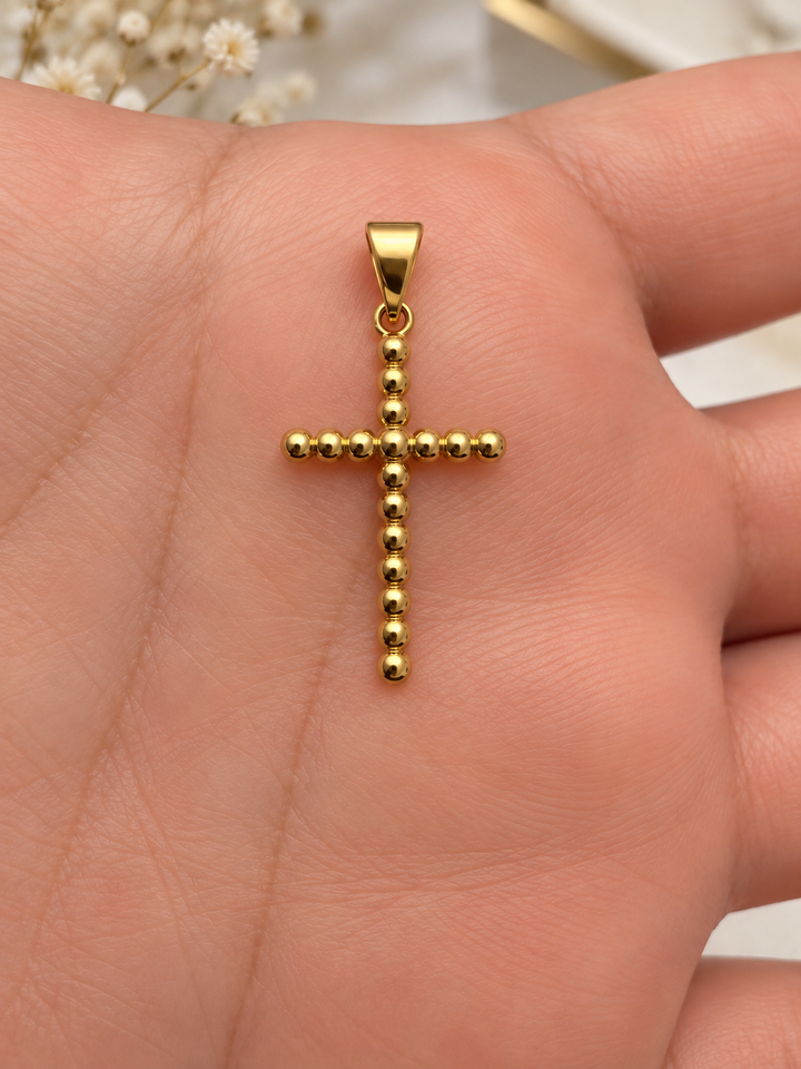 Goldener Kreuzanhänger aus 18 Karat Gelbgold mit kugelförmiger Struktur, auf einer Hand präsentiert.