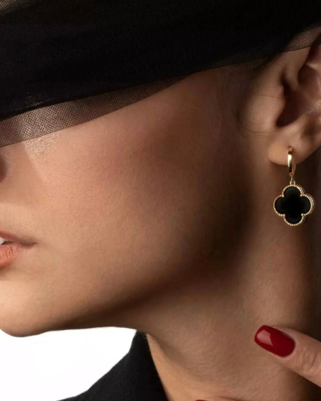 Tragebild: Schwarze Onyxohrringe in Gold – elegant am Ohr getragen mit rotem Nagellack