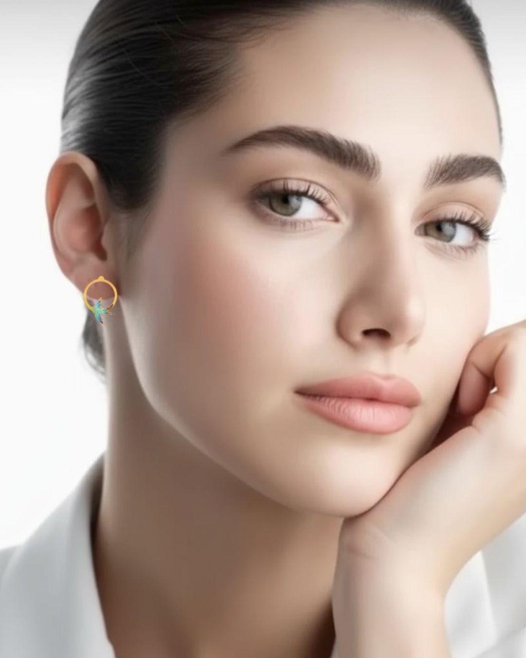 Ohrstecker aus 18k Gelbgold mit emaillierter Schwalbe im Kreis – getragen von einem Model mit weissem Blazer.