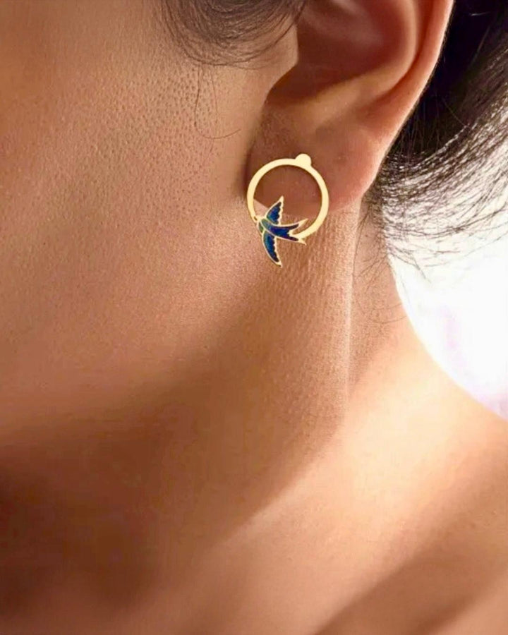Feine 18k Gold Ohrringe mit Schwalbenmotiv in Blautönen – getragen von einem Model als Symbol für Freiheit &amp; Leichtigkeit.