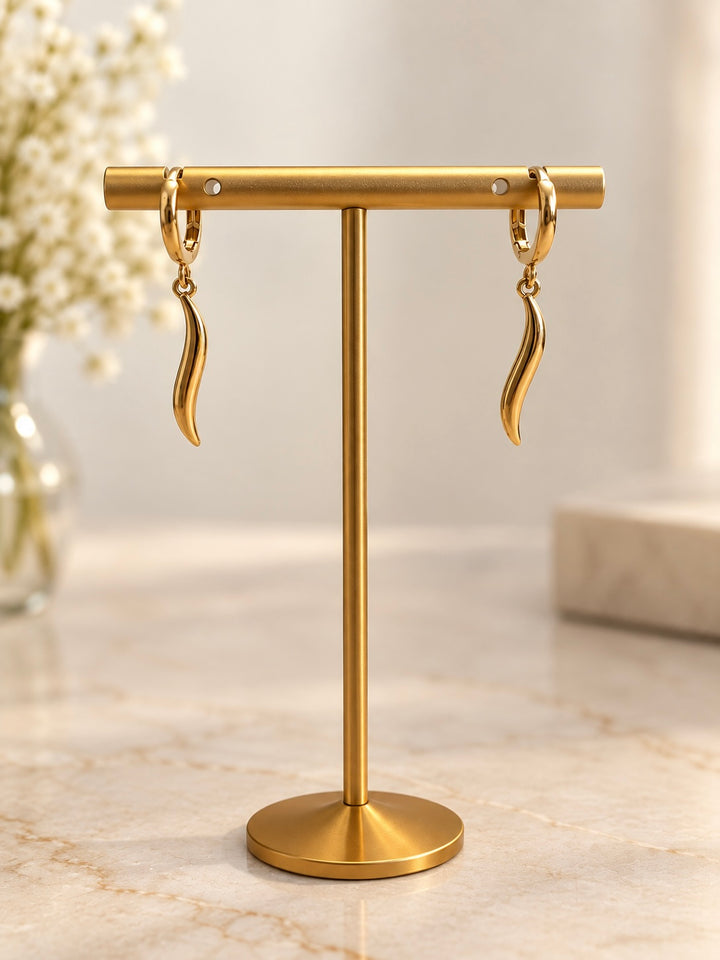 Paar elegante Ohrringe aus Gelbgold mit geschwungenen, flammenförmigen Anhängern, präsentiert an einem goldfarbenen Schmuckständer vor einem hellen, warmen Hintergrund.