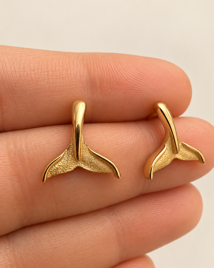 Dom-e Val Walflossen-Ohrstecker aus 18k Gelbgold mit polierten Konturen und fein strukturierter Innenfläche auf der Hand