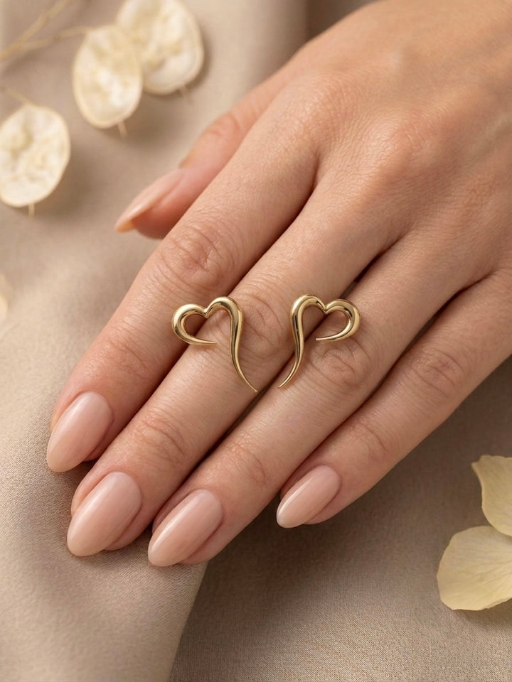 18 Karat Herz-Ohrstecker aus Gelbgold auf einer Hand präsentiert. Elegante Goldohrringe mit modernem, offenem Herzdesign und geschwungener Form – handgefertigter Echtschmuck für Damen, ideal als stilvolles Geschenk oder für den Alltag.