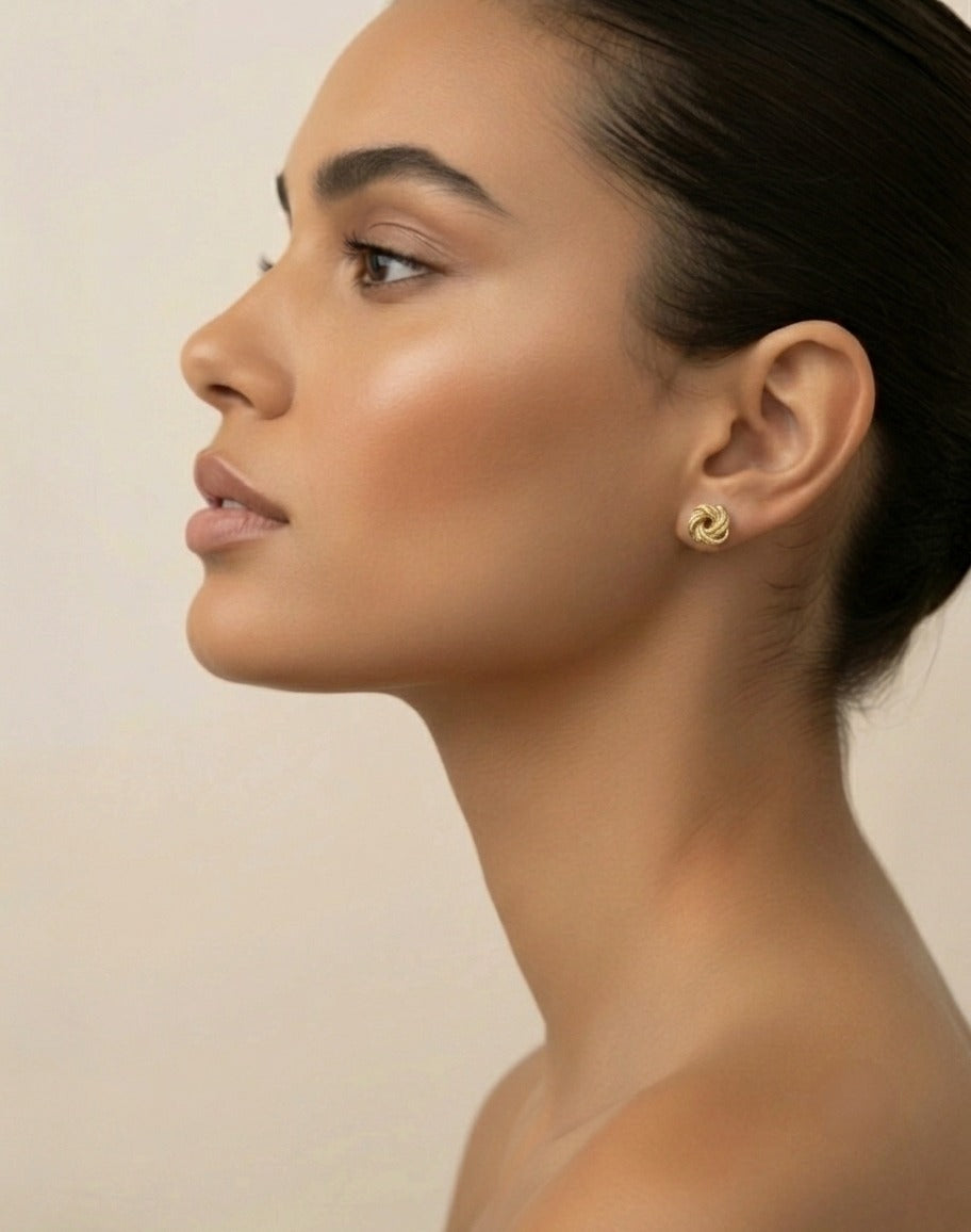 Elegante 18 Karat Gelbgold-Ohrstecker mit gedrehtem Spiraldesign, getragen von einem Model im Seitenprofil. Zeitloser Goldschmuck mit glänzender Oberfläche, ideal für Alltag und besondere Anlässe. Hochwertige Goldohrringe mit 
