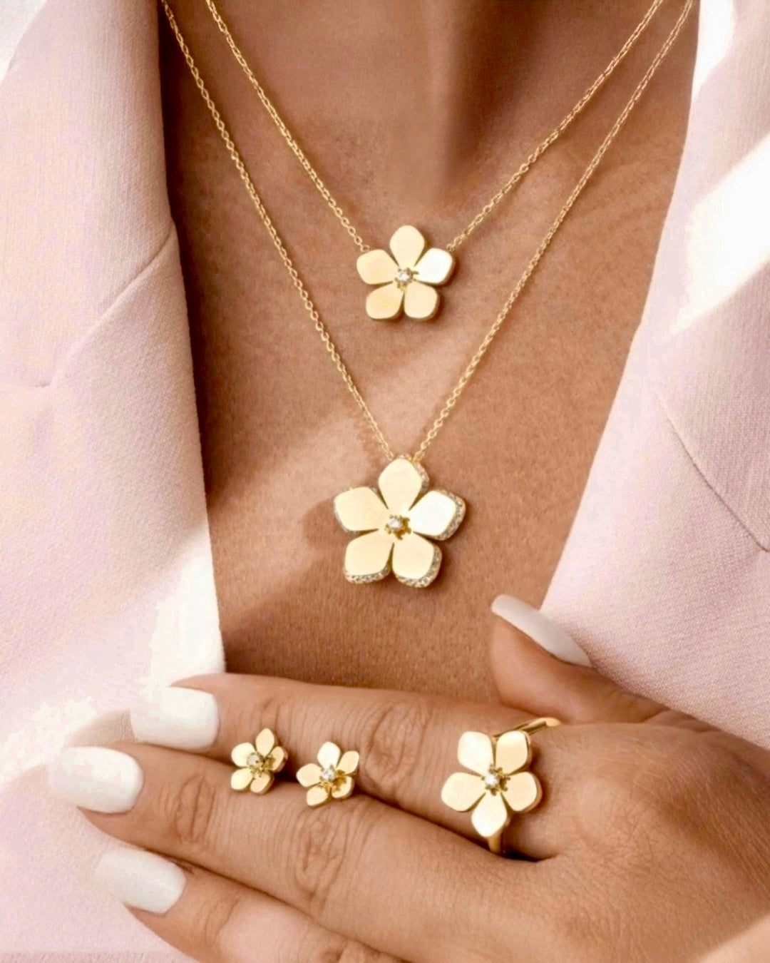 18k Gold-Blütenohrstecker, getragen von einem Modell; kombiniert mit passender Blütenkette und Blütenring. Nahaufnahme des Dekolletés.