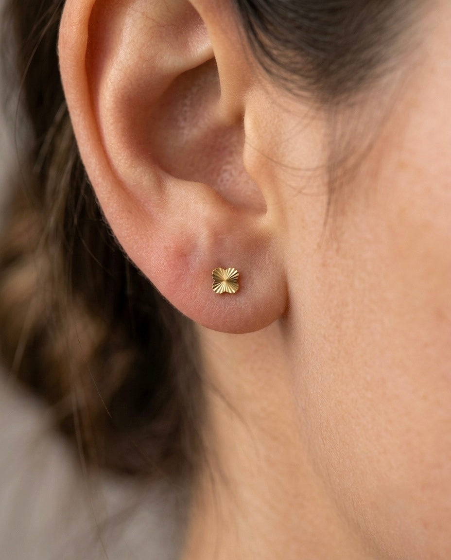 Filigraner Ohrstecker aus 18k Gelbgold mit diamantierter Oberfläche, getragen am Ohr.
