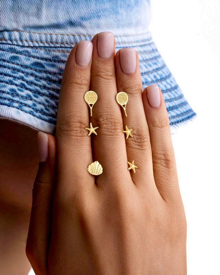 Ohrstecker aus 18k Gelbgold in Tennisraketen-Form, „Raket-e Tennis“, getragen an der Hand im Lifestyle-Setting