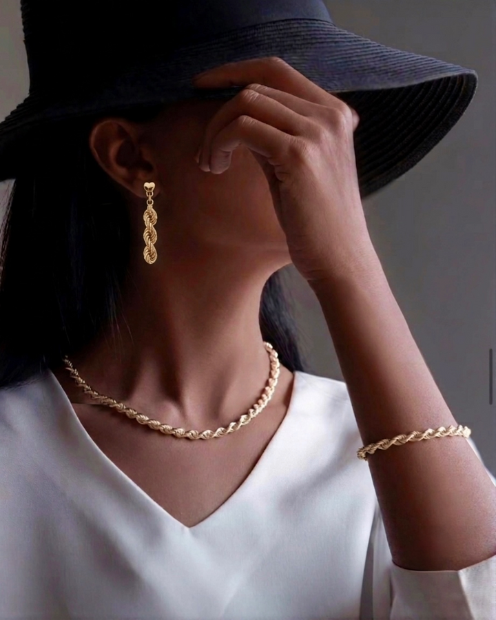 Frau trägt 18k Gelbgold Ohrstecker Tanab-e Tala mit geflochtener Gliederstruktur sowie passende Halskette und Armband