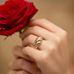 Hand mit dreifarbigem Ring aus Gelbgold, Weissgold hält eine rote Rose – eleganter Schmuck in Nahaufnahme