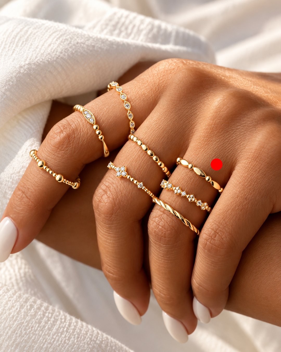 Filigraner Gelbgoldring Daneh mit mandelförmigen Elementen und Goldkügelchen, kombiniert mit weiteren feinen Goldringen an einer Hand.