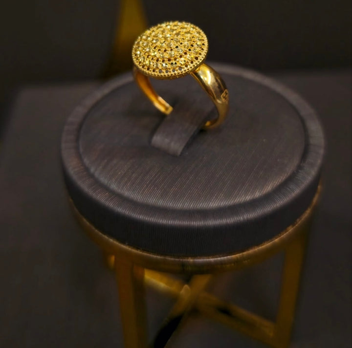Ring aus 18k Gelbgold – Gooy-e Aftab (Sonnenkugel), rundes Design mit fein strukturierten, funkelnden Oberflächenmustern auf breiter Ringschiene, luxuriös und auffällig präsentiert auf dunklem Schmuckständer.