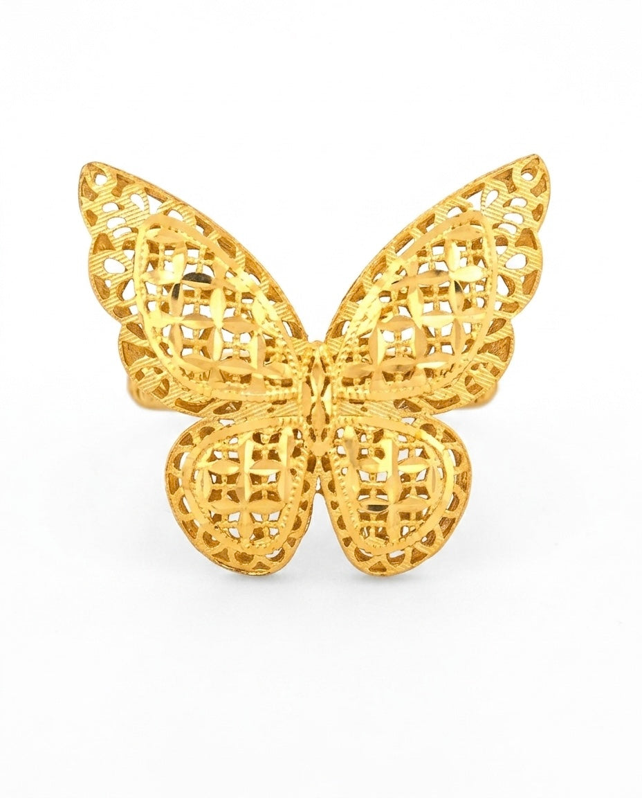 Detailaufnahme eines filigranen Schmetterlings aus 18 Karat Gelbgold. Das kunstvoll durchbrochene Design zeigt fein gearbeitete Ornamente und geometrische Muster in den Flügeln, die dem Schmuckstück eine elegante und luftige Anmutung verleihen. Der Schmetterling ist vor einem schlichten hellen Hintergrund fotografiert, wodurch die warme Goldfarbe und die feinen Details besonders hervorgehoben werden.