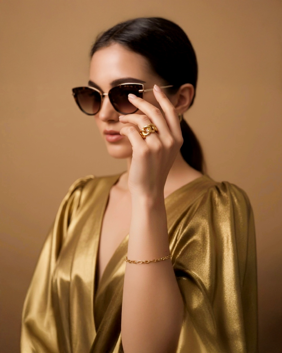 Modell trägt einen massiven 18k Gelbgold-Kettenring und ein feines 18k Gelbgold-Armband, stilvoll kombiniert mit goldfarbenem Kleid und Sonnenbrille – luxuriöser Goldschmuck für zeitlose Eleganz.