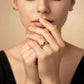 Frau mit geschlossenen Augen trägt einen breiten, hochglanzpolierten 18k Gelbgold-Ring mit Kettenstruktur am Finger – eleganter Goldschmuck in zeitloser, minimalistischer Ästhetik.