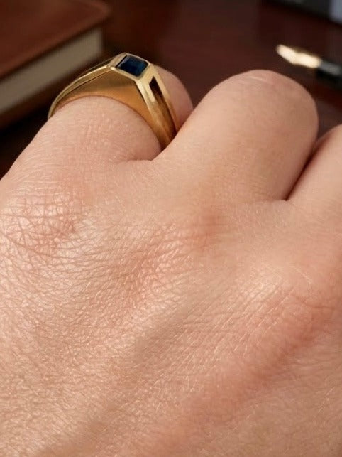 Ring aus 18k Gelbgold mit saphirblauem rechteckigem Stein am Finger getragen