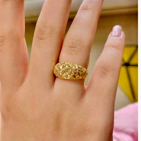 Nahaufnahme einer Hand mit dem Ring „Golbarg-e Pichideh“ aus 18 Karat Gelbgold – detailreiches, verflochtenes Blütenmuster mit erhabener Struktur, das Eleganz und kunstvolle Goldschmiedearbeit vereint.