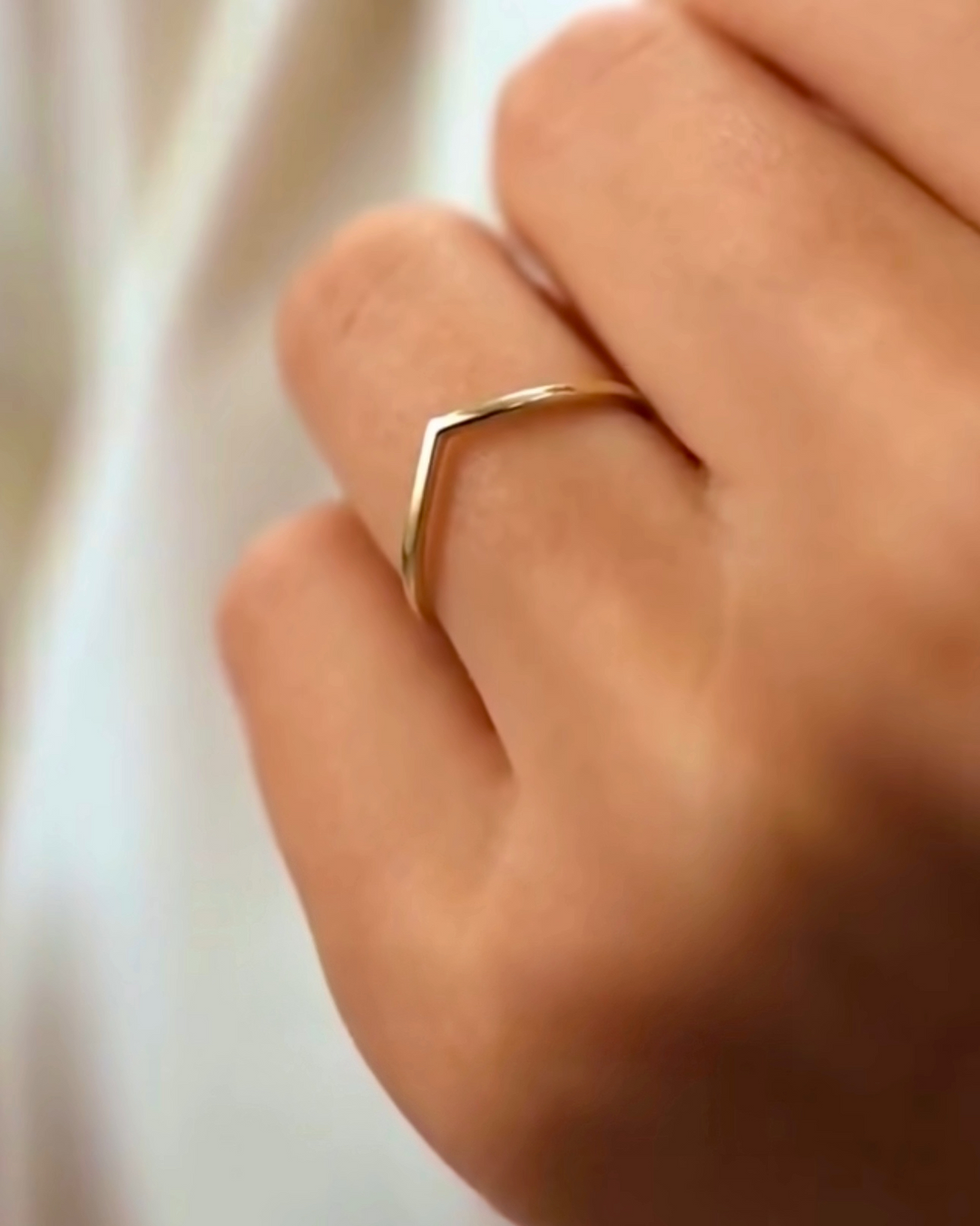 Nahaufnahme einer Hand mit dem Ring „Khatt-e Del“ aus 18 Karat Gelbgold – schlichtes, minimalistisches Design in Form einer feinen V-Linie, symbolisch als „Linie des Herzens“, elegant am Finger getragen.