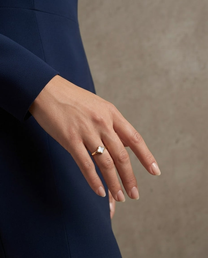 Eleganter Perlmutt Ring aus 18k Gelbgold mit Kleeblatt-Motiv am Finger einer Frau
