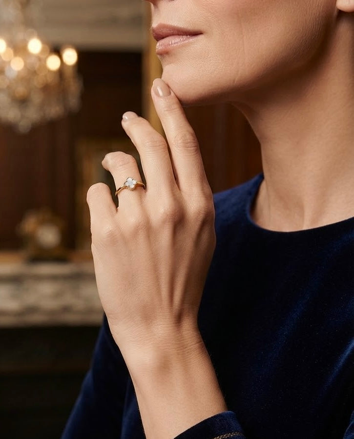 Ring aus 18k Gelbgold mit weißem Perlmutt-Kleeblatt am Finger getragen