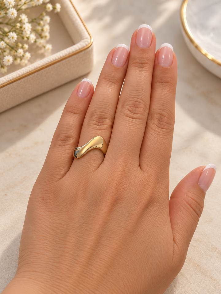 Hand mit Moj-e Tala Ring aus 18k Gelbgold am Ringfinger, asymmetrisches Design mit sanft fliessender Silhouette.