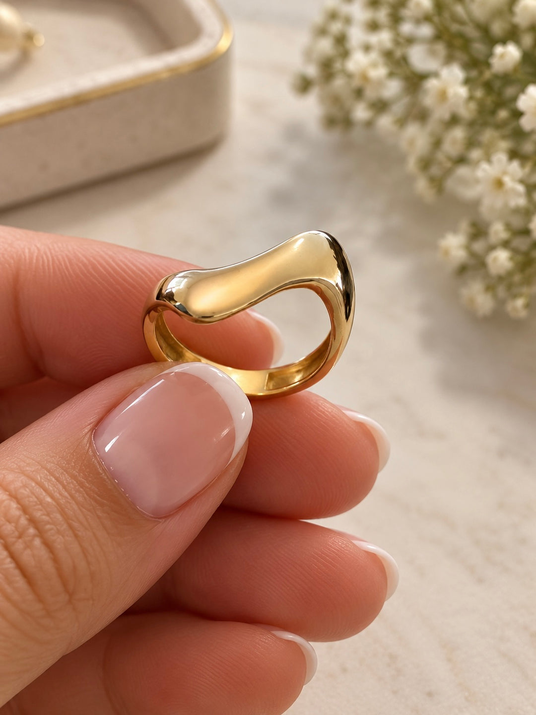 Detailansicht des skulpturalen Moj-e Tala Rings aus 18 Karat Gelbgold mit hochglanzpolierter, wellenförmiger Oberfläche.