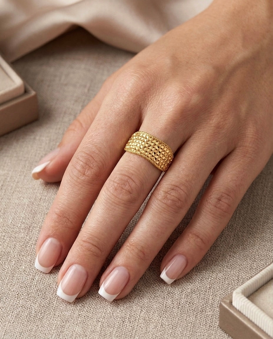 Breiter Damenring aus 18 Karat Gelbgold mit aufwendig strukturierter, pyramidenförmiger Oberfläche. Der elegante Goldring wird an der Hand getragen und besticht durch sein luxuriöses Design sowie die warme Ausstrahlung des hochglänzenden Goldes.