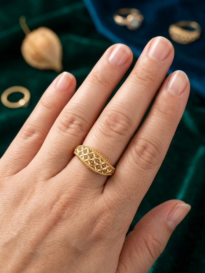 Filigraner Damenring aus 18 Karat Gelbgold mit floralem Blütenmuster, getragen an der Hand vor edlem grünem Samt – eleganter Goldring von ZIBA GOLD.