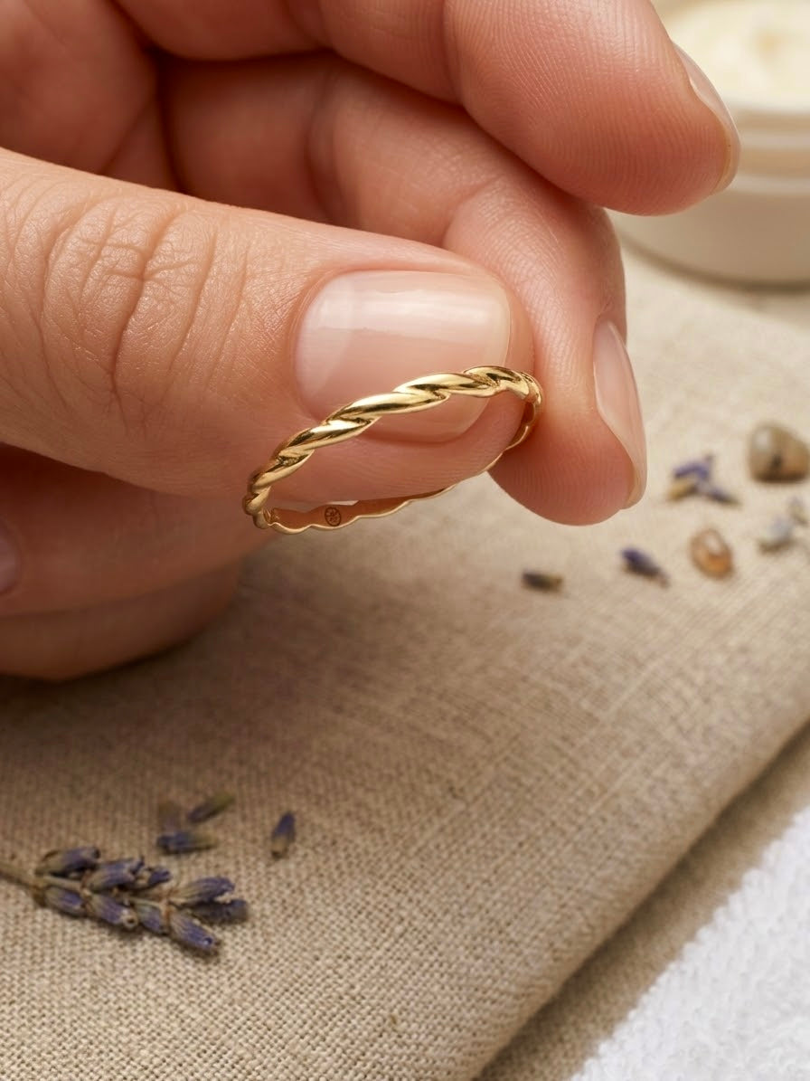 Filigraner gedrehter Ring aus 18 Karat Gelbgold mit feiner Kordelstruktur, handgehalten vor natürlichem Leinenstoff mit Lavendel.