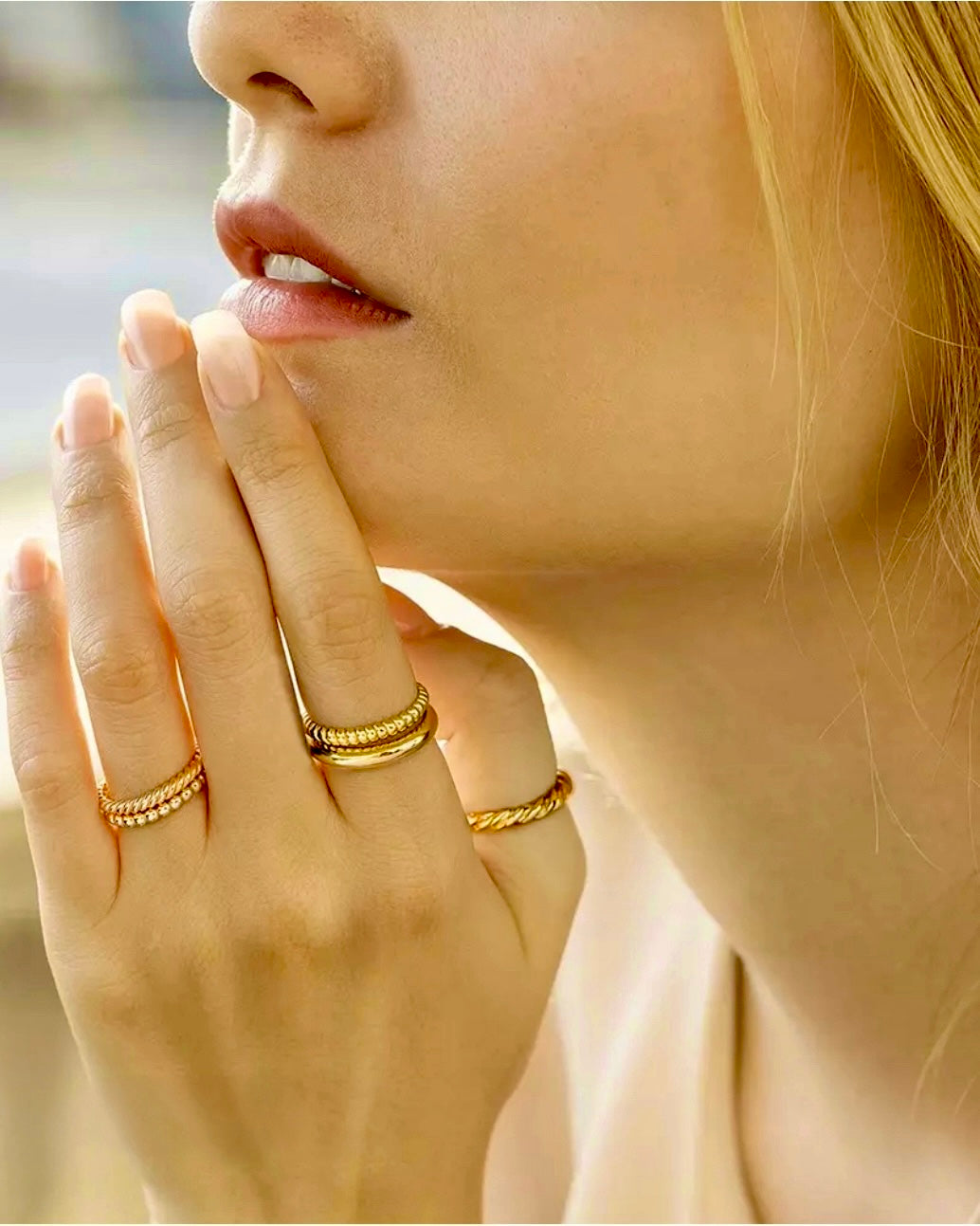 Nahaufnahme einer Frau, die ihre Hand an das Gesicht legt und mehrere Ringe trägt – darunter der Ring „Reshhe-ye Tala“ aus 18 Karat Gelbgold mit feiner, gedrehter Goldfaden-Struktur, die Eleganz und Schlichtheit verbindet.