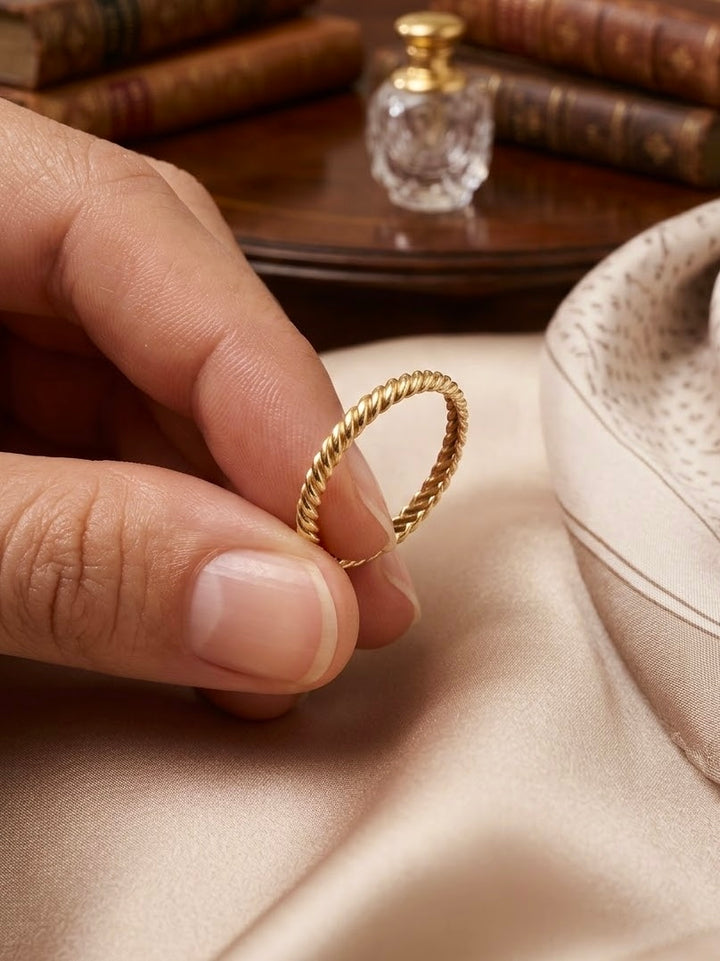 Filigraner gedrehter Ring aus 18 Karat Gelbgold mit feiner Kordelstruktur, elegant zwischen den Fingern gehalten – Ziba Gold
