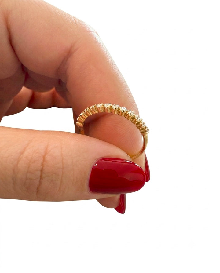 18 Karat Gelbgoldring mit funkelnden Diamanten in filigraner Fassung, gehalten zwischen Fingern mit rotem Nagellack vor weissem Hintergrund.