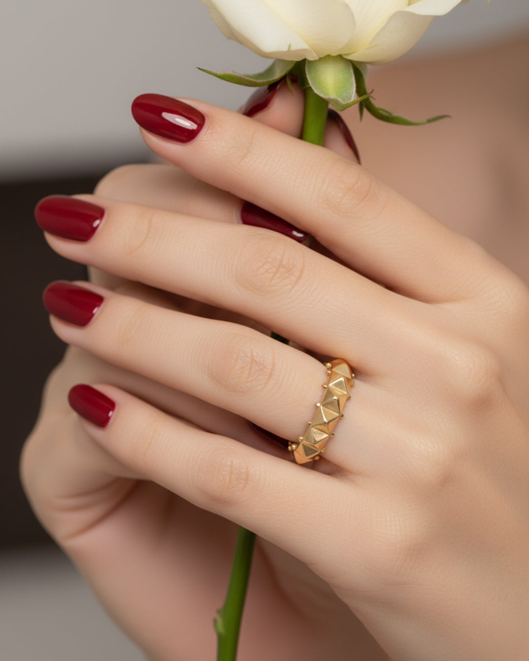 Frau trägt 18k Goldring mit geometrischem Muster – Handaufnahme mit weisser Rose