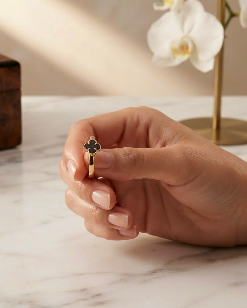 Filigraner Kleeblatt Ring aus 18k Gelbgold mit schwarzem Onyx in der Hand gehalten
