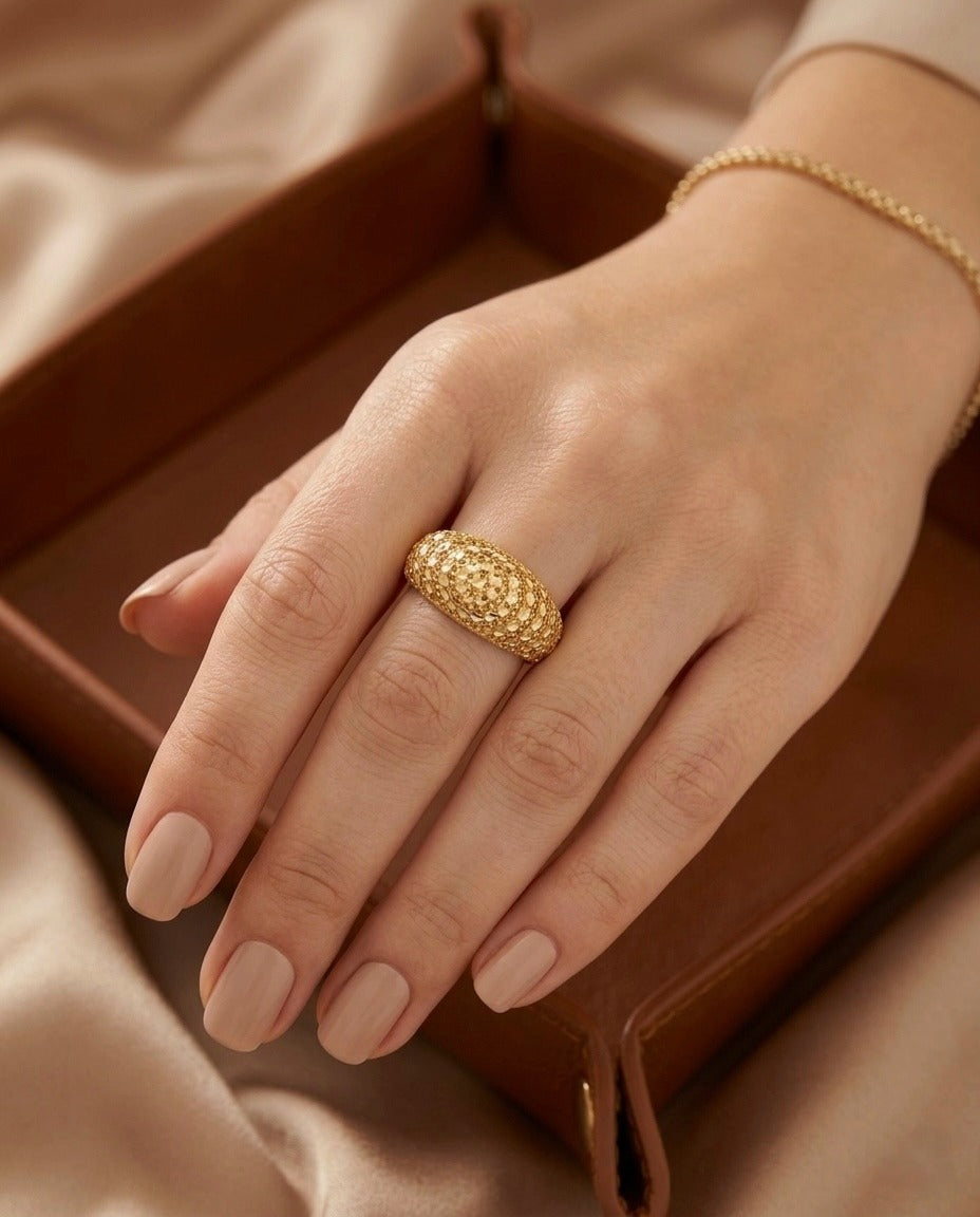 Eleganter Damenring aus 18 Karat Gelbgold, getragen an der Hand. Die kunstvoll strukturierte Oberfläche mit kreisförmigem Ornament verleiht dem handgefertigten Ring eine luxuriöse Ausstrahlung und macht ihn zu einem stilvollen Blickfang für besondere Anlässe und den Alltag.