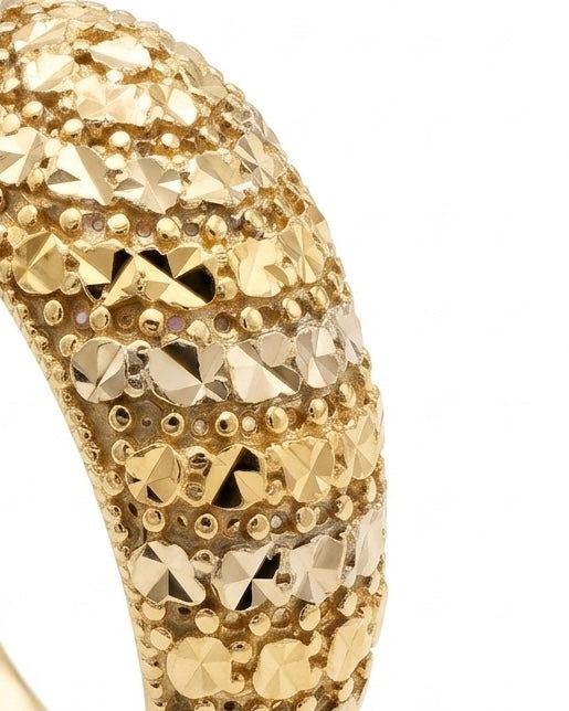 Nahaufnahme eines handgefertigten Rings aus 18 Karat Gelbgold mit aufwendig diamantierter Struktur. Die facettierten Goldflächen reflektieren das Licht intensiv und verleihen dem exklusiven Schmuckstück eine luxuriöse, funkelnde Ausstrahlung.